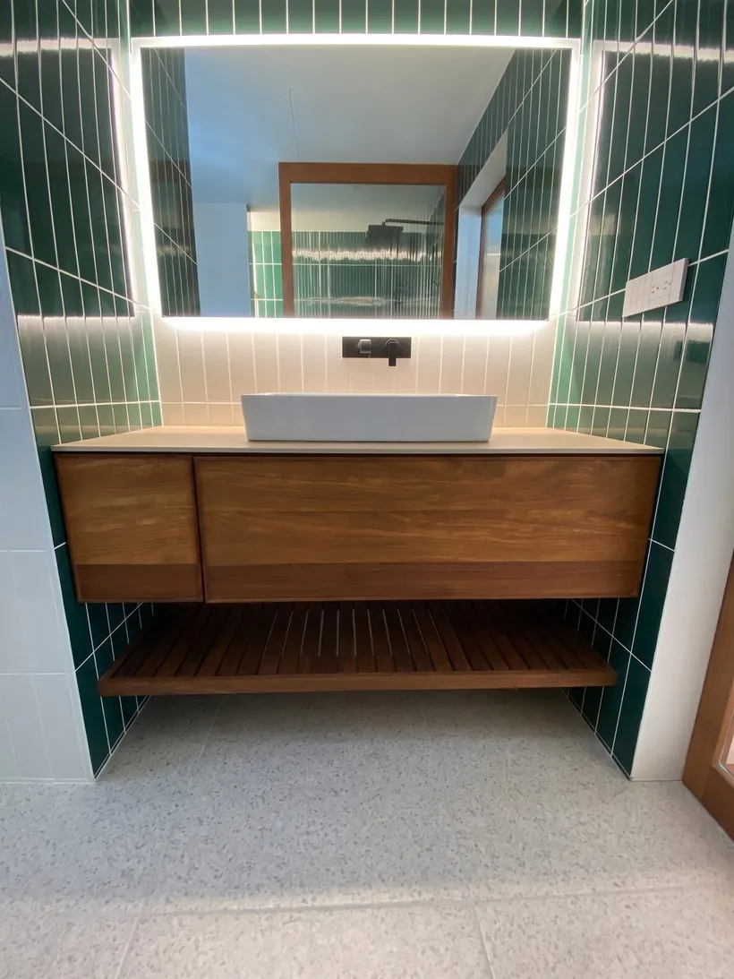 Mueble de baño suspendido en madera con azulejo verde y espejo retroiluminado en Tijuana