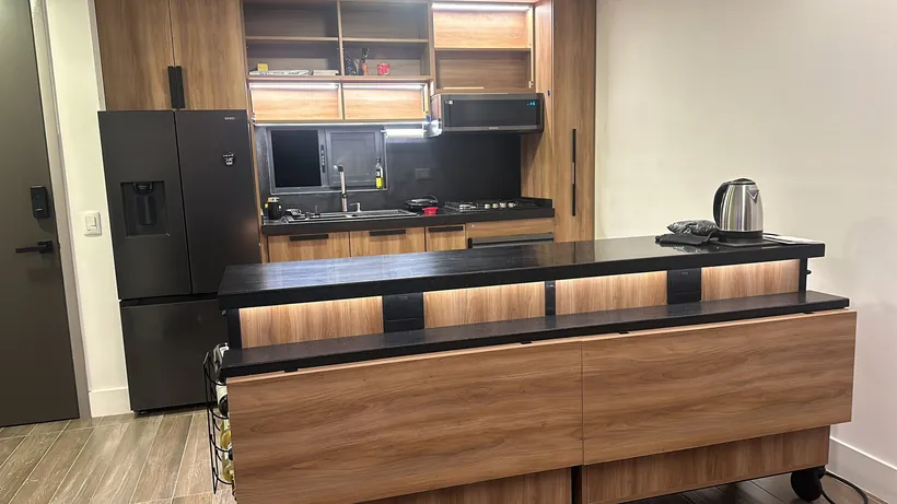 Cocina integral de madera con isla y cubierta negra en Tijuana
