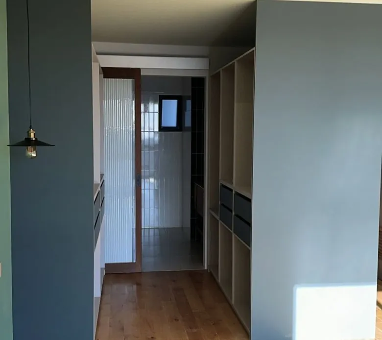 Walking closet con piso de madera y puerta corrediza de cristal en Tijuana