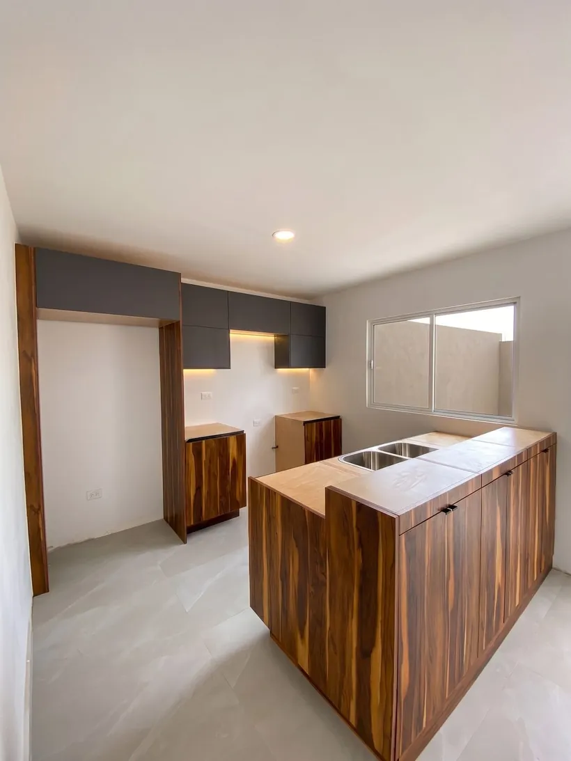 Vista de la cocina con isla y muebles superiores en gris