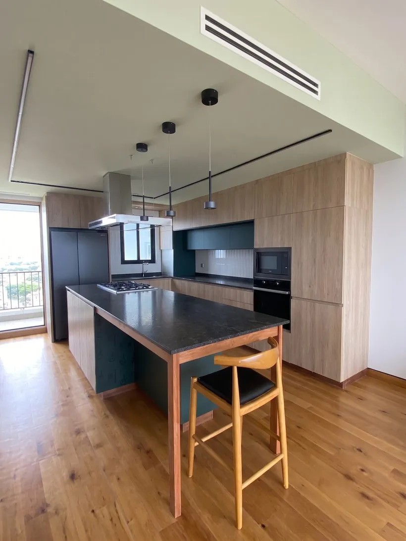 Cocina integral abierta con isla y bancos, vista hacia el ventanal
