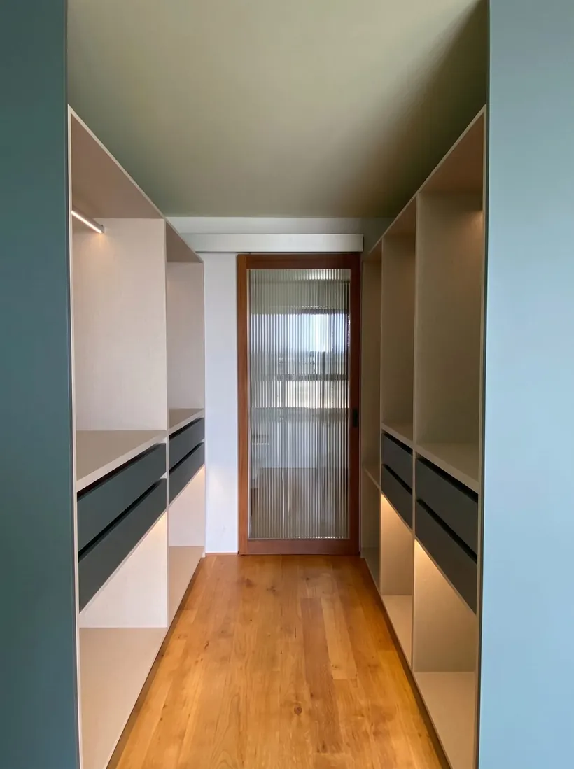 Vestidor a la medida visto a lo largo del pasillo, con cajonería a ambos lados